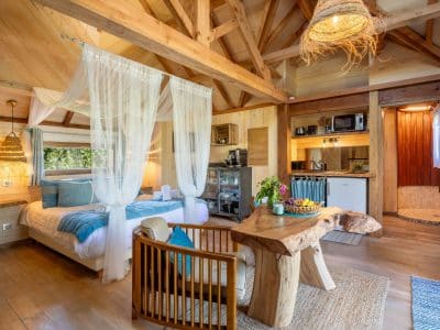 Cabane en bois avec lit à baldaquin et décor naturel, ambiance chaleureuse.