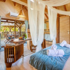 Hébergement insolite en Aquitaine : cabane en bois avec lit douillet et vue sur la terrasse.
