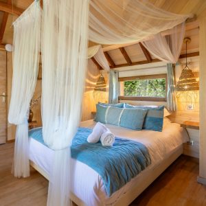 Chalet en bois avec lit douillet, drapés légers et ambiance chaleureuse en Aquitaine.