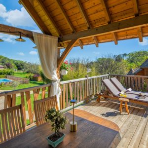 Charmant chalet en bois avec vue sur la piscine et la nature environnante.