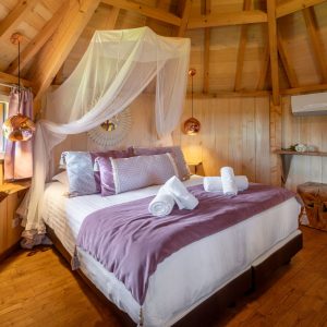 Cabane en bois en Aquitaine, lit douillet avec drap en voile et décor chaleureux.