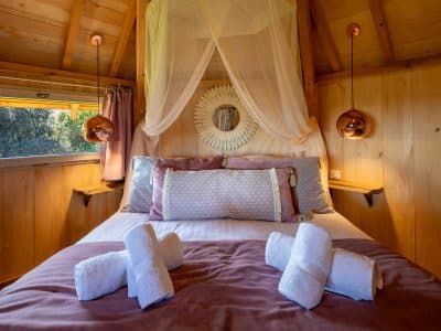 Cabane en bois cosy avec lit douillet et décoration chaleureuse.