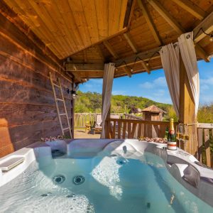 Hébergement insolite en Aquitaine avec jacuzzi sur terrasse en bois et vue verdoyante.