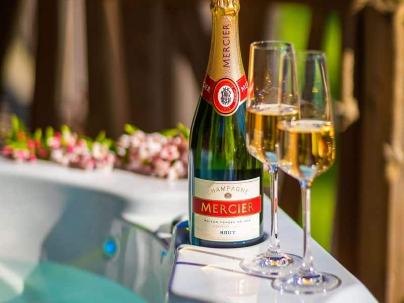 Bain à remous romantique avec champagne Mercier et flûtes, parfait pour une escapade.