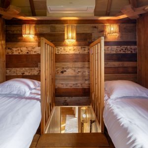 Chalet en bois avec deux lits séparés et éclairage chaleureux en Aquitaine.