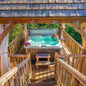 Cabane perchée en Aquitaine avec jacuzzi, entourée de verdure et fleurs.