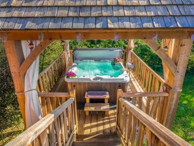 Cabane perchée en Aquitaine avec jacuzzi, entourée de verdure et fleurs.