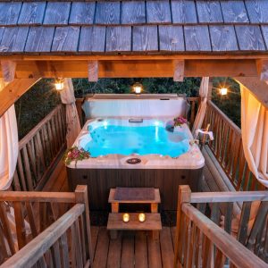 Cabane en bois avec jacuzzi, éclairage doux et ambiance romantique en Aquitaine.
