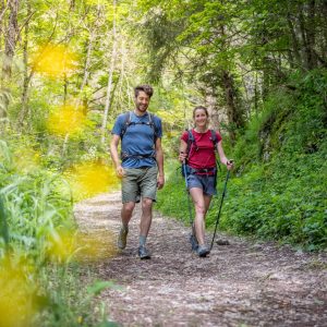 Couple en randonnée sur un sentier verdoyant en Auvergne-Rhône-Alpes, hébergement insolite.