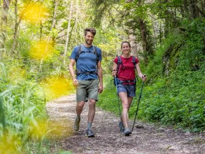 Couple en randonnée sur un sentier verdoyant en Auvergne-Rhône-Alpes, hébergement insolite.