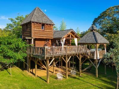 Cabane perchée en bois avec terrasse, entourée de verdure en Aquitaine.