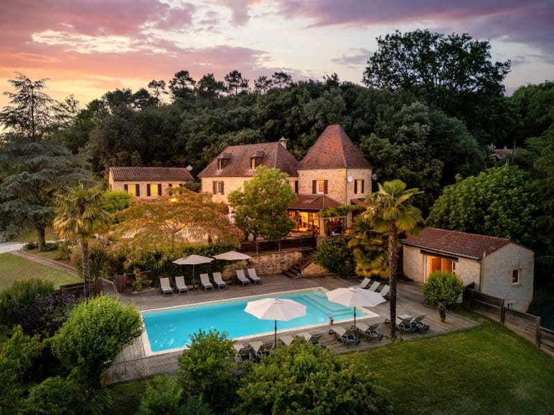 Charmante maison de campagne avec piscine, entourée de verdure et palmiers.