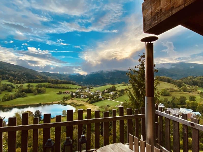 Chalet en bois avec terrasse, vue panoramique sur le lac et les montagnes.