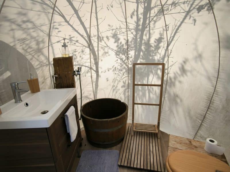 Hébergement insolite : salle de bain avec baignoire en bois et lumière naturelle.