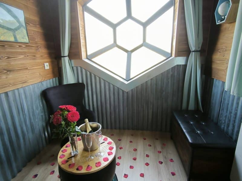 Chalet romantique avec vue hexagonale, décoré de pétales de rose et champagne.