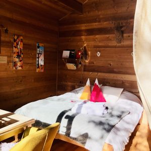 Chalet en bois cosy avec lit douillet et décor montagnard coloré.