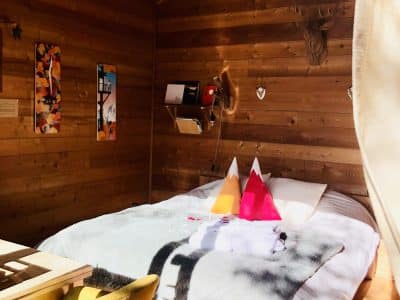 Chalet en bois cosy avec lit douillet et décor montagnard coloré.