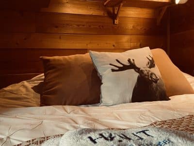 Cabane en bois cosy en Auvergne, avec oreillers douillets et décor nature.