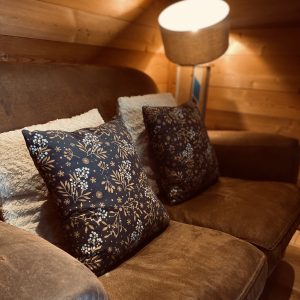 Cocon en bois en Auvergne-Rhône-Alpes, avec un canapé confortable et coussins fleuris.