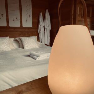 Chalet en bois avec lit douillet et lampe chaleureuse, ambiance cocooning.