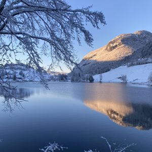 Hébergement insolite en Auvergne-Rhône-Alpes, vue sur un lac gelé et montagnes enneigées.