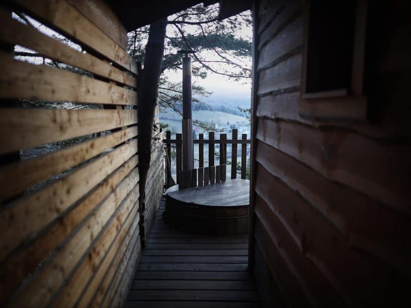 Cabane perchée en bois avec vue sur la nature, ambiance chaleureuse et intime.