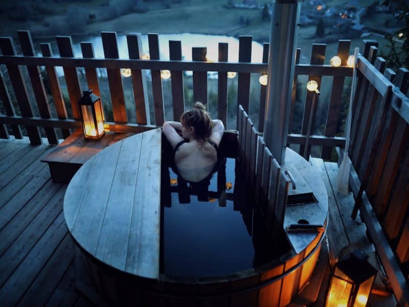 Cabane en bois avec baignoire extérieure, vue panoramique sur la nature.