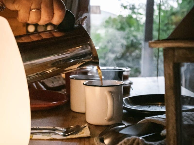 Cottage chaleureux avec café fumant servi dans des tasses blanches, ambiance conviviale.