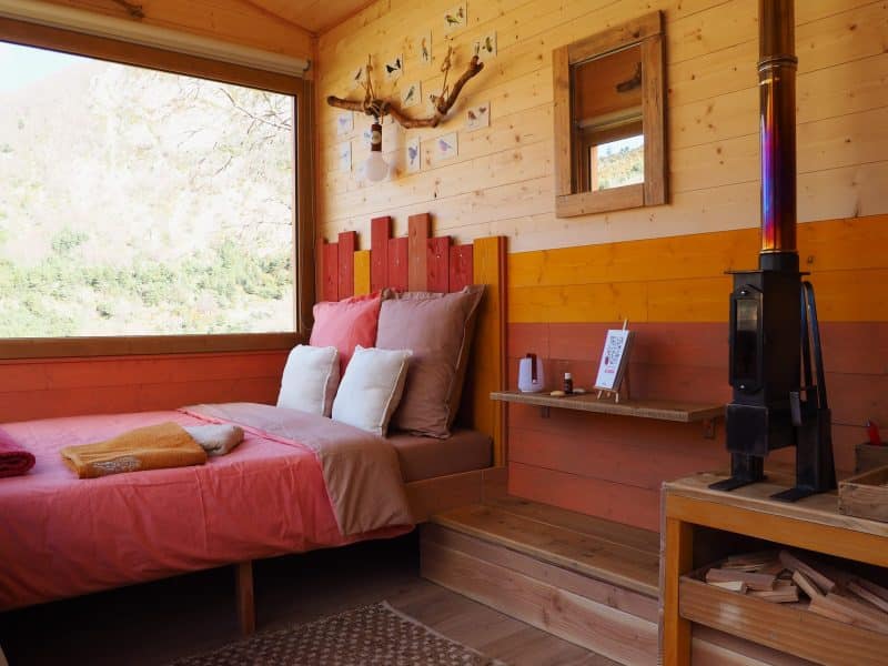 Chalet en bois avec lit douillet et vue panoramique sur la nature en Auvergne-Rhône-Alpes.