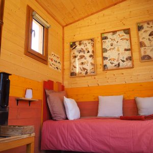 Cabane en bois chaleureuse avec poêle, décorée de tableaux naturels.