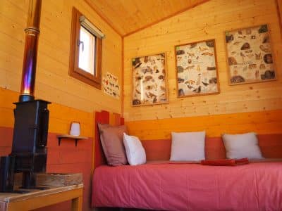 Cabane en bois chaleureuse avec poêle, décorée de tableaux naturels.