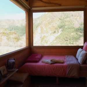 Cabane en bois avec vue panoramique sur les montagnes, lit douillet et décor chaleureux.