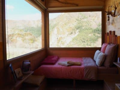 Cabane en bois avec vue panoramique sur les montagnes, lit douillet et décor chaleureux.