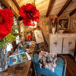 Cabane artistique en Grand-Est, décorée de fleurs rouges et dœuvres dart.