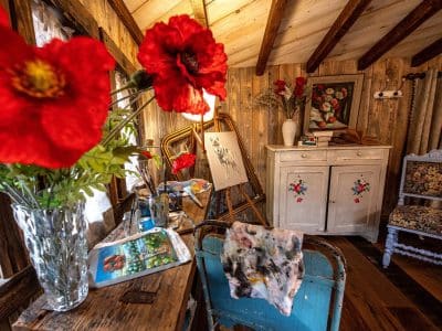 Cabane artistique en Grand-Est, décorée de fleurs rouges et dœuvres dart.