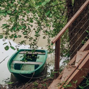 Hébergement insolite en Nouvelle-Aquitaine, bateau vert amarré près dun arbre.