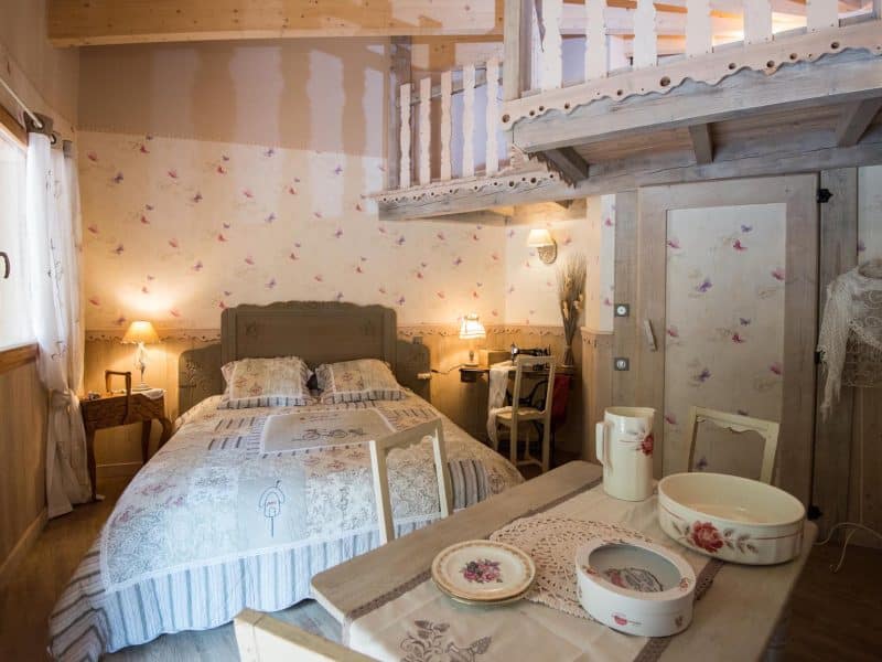 Chalet romantique en bois avec mezzanine, décor floral et ambiance chaleureuse.