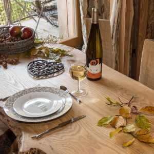 Hébergement insolite en bois dans le Grand-Est, avec une table décorée et une bouteille de vin.