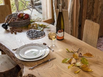Hébergement insolite en bois dans le Grand-Est, avec une table décorée et une bouteille de vin.