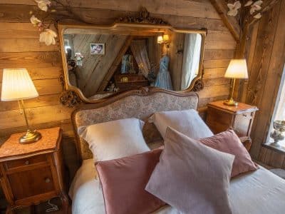Chalet en bois chaleureux avec lit douillet et miroir ancien, ambiance cosy.