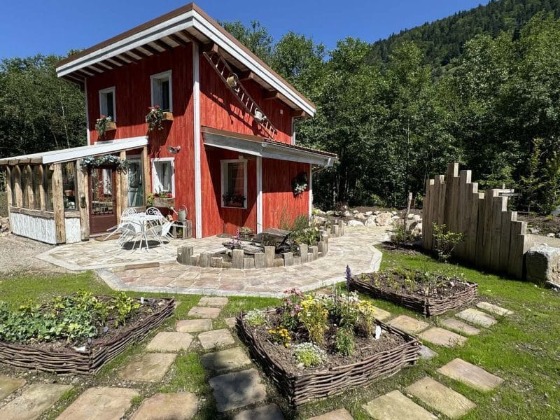 Charmante maison en bois rouge avec jardin fleuri, située en Grand-Est.