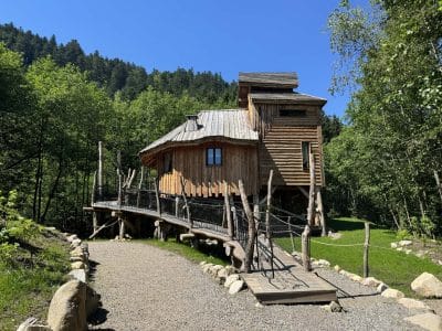 Cabane perchée en bois avec passerelle, entourée de verdure à Grand-Est.