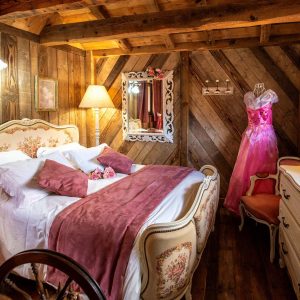Chalet romantique en bois avec lit double et décoration vintage élégante.