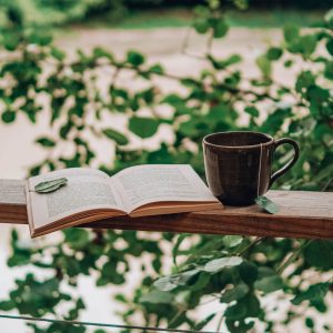Hébergement insolite en Nouvelle-Aquitaine : un livre ouvert et une tasse sur un balcon verdoyant.