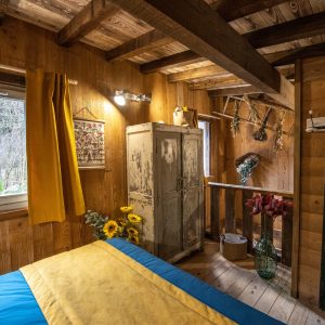 Chalet en bois chaleureux avec un lit coloré et des fleurs décoratives.