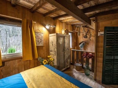 Chalet en bois chaleureux avec un lit coloré et des fleurs décoratives.