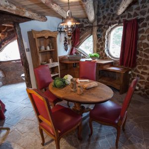 Hébergement insolite en pierre avec mobilier en bois et fenêtres arrondies.