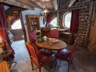 Hébergement insolite en pierre avec mobilier en bois et fenêtres arrondies.