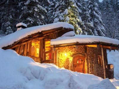 Cabane en bois au cœur de la neige, illuminée par une douce lumière chaleureuse.