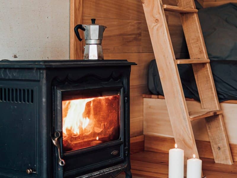 Chalet cosy avec poêle à bois, échelle en bois et ambiance chaleureuse.
